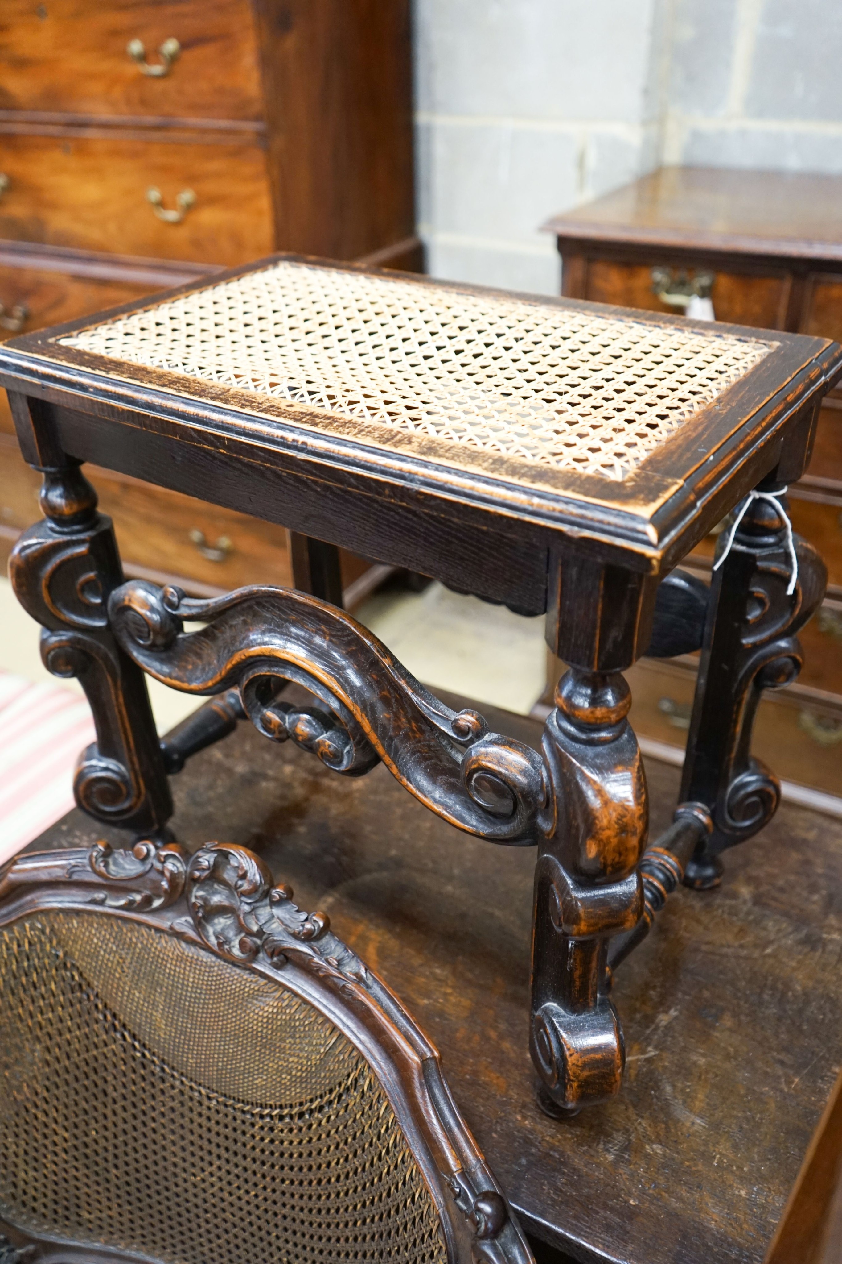 A French style carved walnut frame bergere with caned panels on cabriole legs, length 70cm, depth 52cm, height 86cm together with a Carolean style caned stool